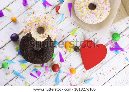Donut on a wooden white background and a scattering of sweet ornaments