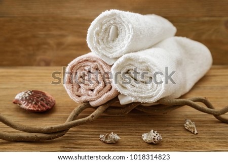 Stack of bath towels on wooden background. White and pink fluffy towels. Spa concept. Toned photo.