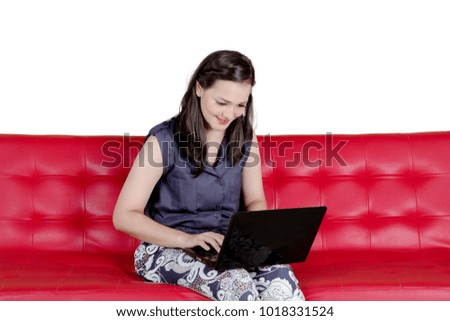 Picture of beautiful woman sitting on the couch while using a laptop, isolated on white background