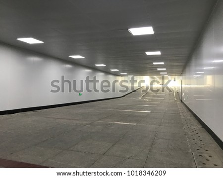 Empty underground pedestrian pathway with lights on. Modern tunnel with nobody at nice perspective.