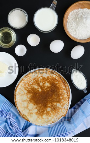 Russian pancakes with ingredients for cooking on black background. Recipe. Overhead food shots