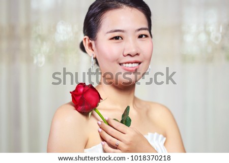 Beautiful Asian look woman in white dress holding rose flower, selected focus