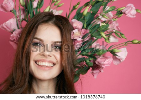  joyful woman with flowers on a pink background, portrait                              