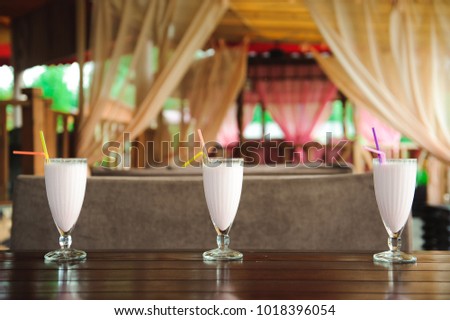 Three jars of pink berry milkshakes with straws on old wooden table