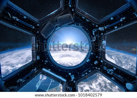 View from a porthole of space station on the Earth background. Elements of this image furnished by NASA. Royalty-Free Stock Photo #1018402579