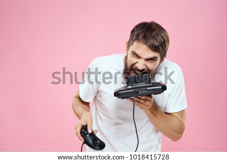  man with a beard holds a game console on a pink background                              