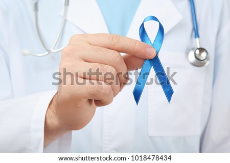 Doctor holding blue ribbon, closeup. Cancer awareness concept Royalty-Free Stock Photo #1018478434