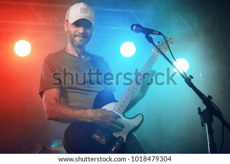 The guitarist performs on stage. Stage light, smoke.