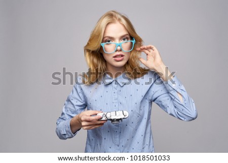 a woman in glasses holds an old camera on a light background                               