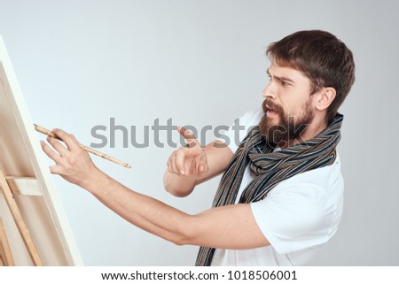painter paints on canvas on a light background                               