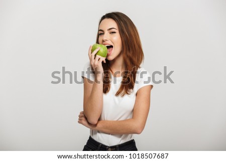 Portrait of a cheerful young woman eating green apple isolated over white background Royalty-Free Stock Photo #1018507687