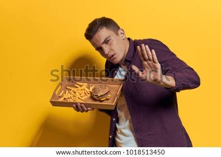  man with a tray of fast food on a yellow background                              