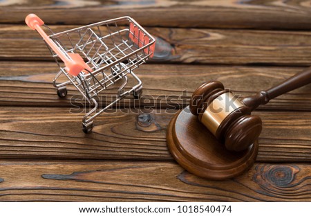 hammer of the judge, a trolley from a supermarket on a wooden background. consumer rights Protection. Royalty-Free Stock Photo #1018540474