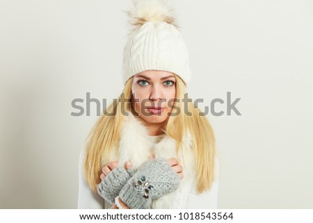 Winter fashion. Young blonde woman wearing fashionable wintertime clothes white fur scarf, woolen cap and gloves, studio shot