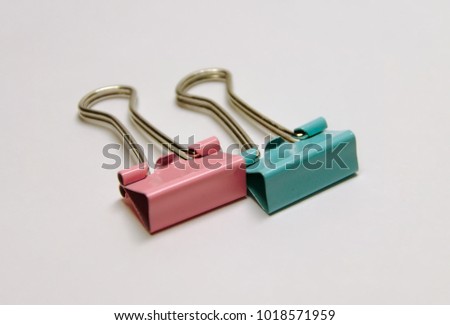 Binder clips on white background. Blue and pink clips for paper