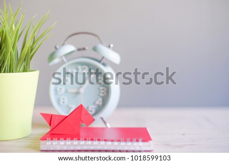 Creative lay out.Red dog paper origami with blur alarm clock, green tree and red note book in background.rabbit origami with copy space.Chinese New Year concept. Selective Focus shot.