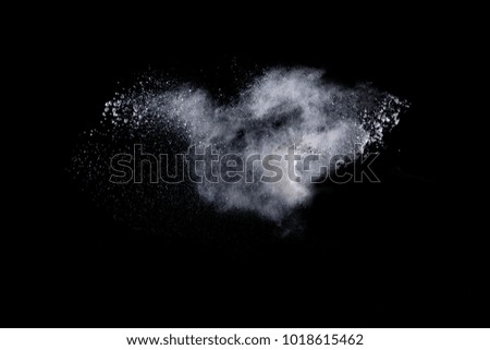 Freeze motion of white dust explosion on black background. Stopping the movement of white powder on dark background. 