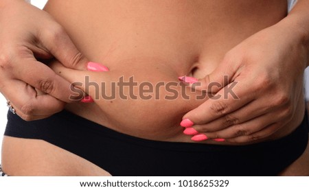 Woman pinching a fat on her waist on white background