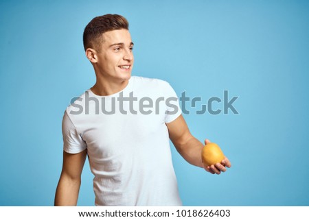  man smiling holding an orange on a blue background                              