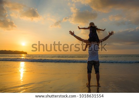 Father and daughter playing at the sunset beach
