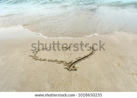 Hand drawing of heart shaped on beach background, sand texture and wave from sea, love is all around, Valentine's day concept  