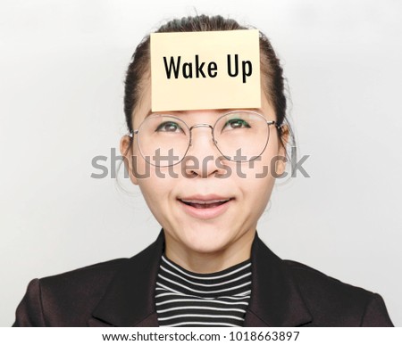 Asian women wearing eyeglasses, diagonal striped shirt and a black suit with a note on the forehead write the word "Wake up"