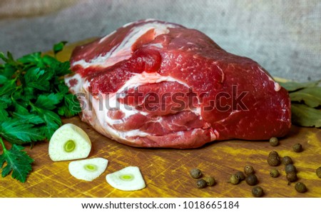 Raw black angus beef bound with rope in craft paper on cutting board. Aged prime marble meat, herbs and spices rustic wood against white brick wall background with copy space