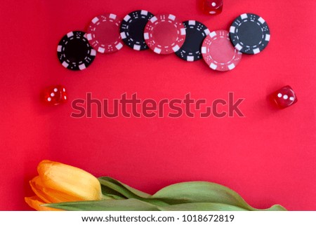 Poker set. Festive greetings to Women's day. Group of poker chips, dices and yellow tulip on red background. Top view, copy space