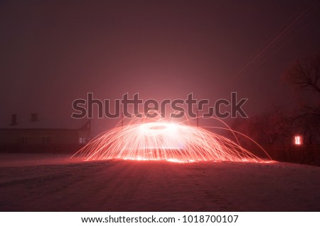 Bright crimson sparks in fog, steel wool photography, beautiful sight in winter night