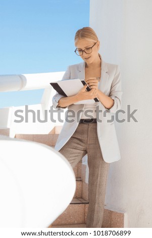 Young blond businesswoman taking notes while standing