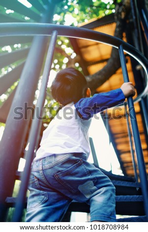 Soft focus at children walking up the stairs. / The kid try to climb up the spiral staircase / composing picture with sunlight / concept of ambitious and confidential and never give up