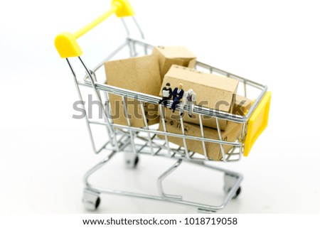 Miniature people: Group businessman sitting on shopping cart for retail business. Image use for online and offline shopping, marketing place world wide.