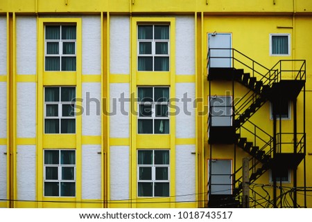 Pattern texture of yellow building with fire escape steel ladder in Bangkok, Thailand
