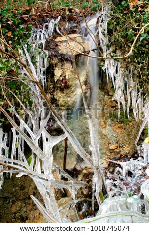 Icicles around a small rock face stream in cold weather