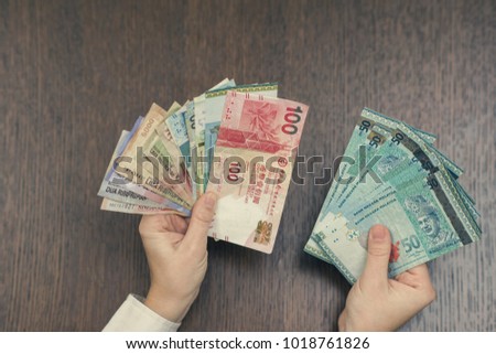 Female hand with money of south-east Asia. Currency of Hong Kong, Indonesia, Malaysia, Thai, Singapore dollar. Travel concept. exchange