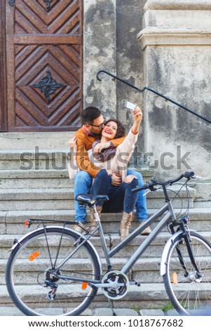Young smiling couple using mobile phone while sitting on the stairs.