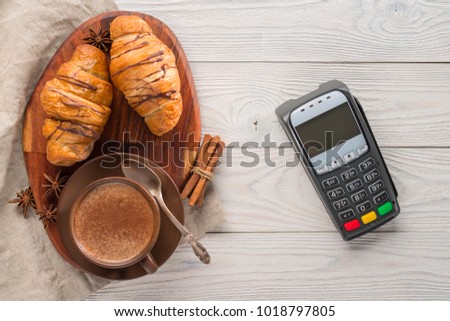 composition of coffee and croissants with bank payment terminal on a wooden background