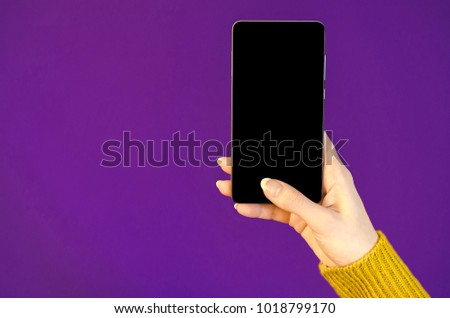 Woman hands warm yellow sweater using cellphone holding smart mobile phone with oled display on ultra violet color of year background. Close up Flat Lay bussines composition Top view communica Royalty-Free Stock Photo #1018799170