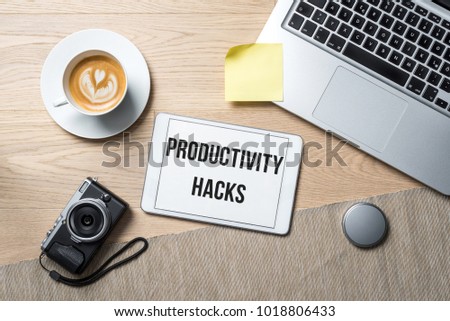 Productivity hacks writing on tablet with camera, coffee mug and laptop lying on photography office desk as flat lay