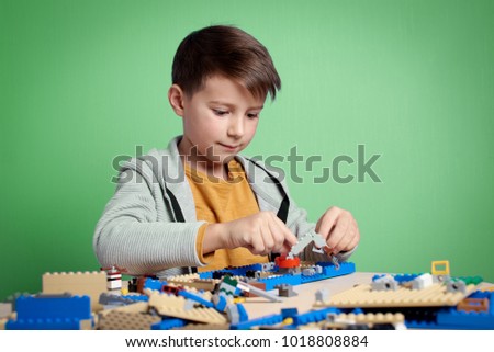 Caucasian boy is carefully building with toy construction set.