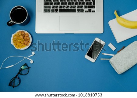 Blue workplace with laptop, fruits and black tea cup. Top view. Flat lay