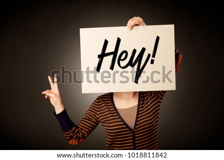 Young casual woman hiding behind a greeting drawn on paper