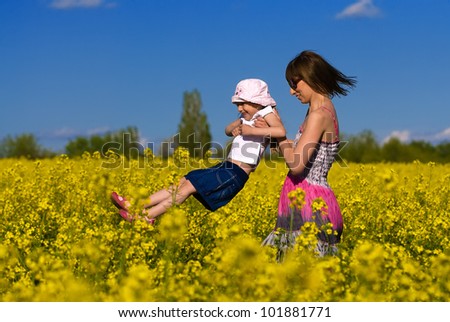 Young mother and her daughter having fun at the colza field