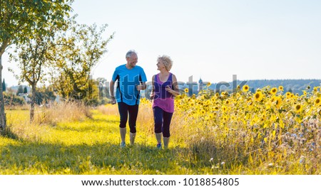 Full length rear view of two healthy senior people jogging on a country road against clear blue sky in summer Royalty-Free Stock Photo #1018854805