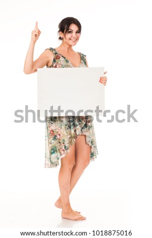 A beautiful woman in a dress holds a white billboard in her hands for advertising, logo, business cards, stock. White card, banner. High model- the brunette shows the wounded poses and emotions.