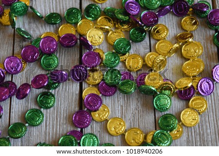 Gold,purple, and green Mardi Gras beads against a wood background