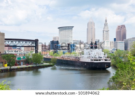 A Great Lakes self unloading bulk carrier ship negotiates a sharp curve in the Cuyahoga River with the downtown Cleveland, Ohio skyline in the background