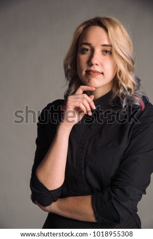 portrait of serious young woman with colored hair in black shirt isolated on gray studio background
