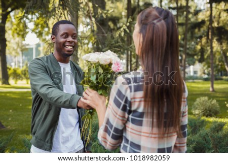 Man giving flowers for his beautiful girlfriend, having anniversary date in park, copy space
