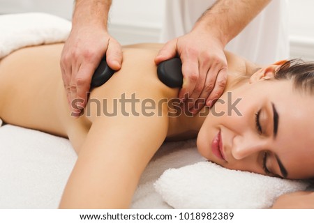 Beautiful woman getting hot stones arm massage in spa salon. Beauty treatment therapy, wellness and relaxation concept Royalty-Free Stock Photo #1018982389